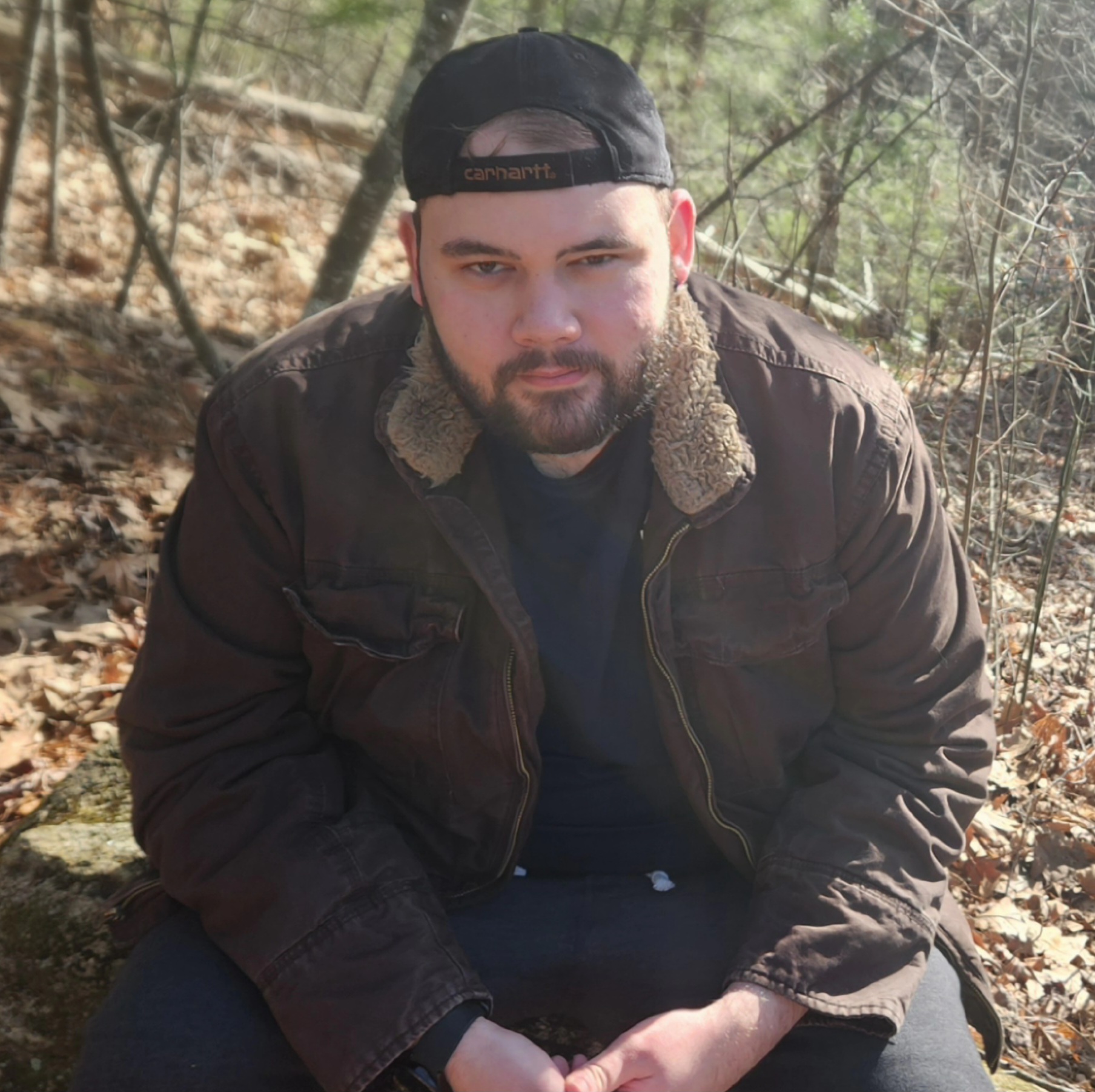 A photo of Cody sitting in the woods.